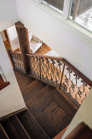 Eine Holztreppe mit Metallgeländer, die zu einem Raum mit weißer Wand und Fenster führt.