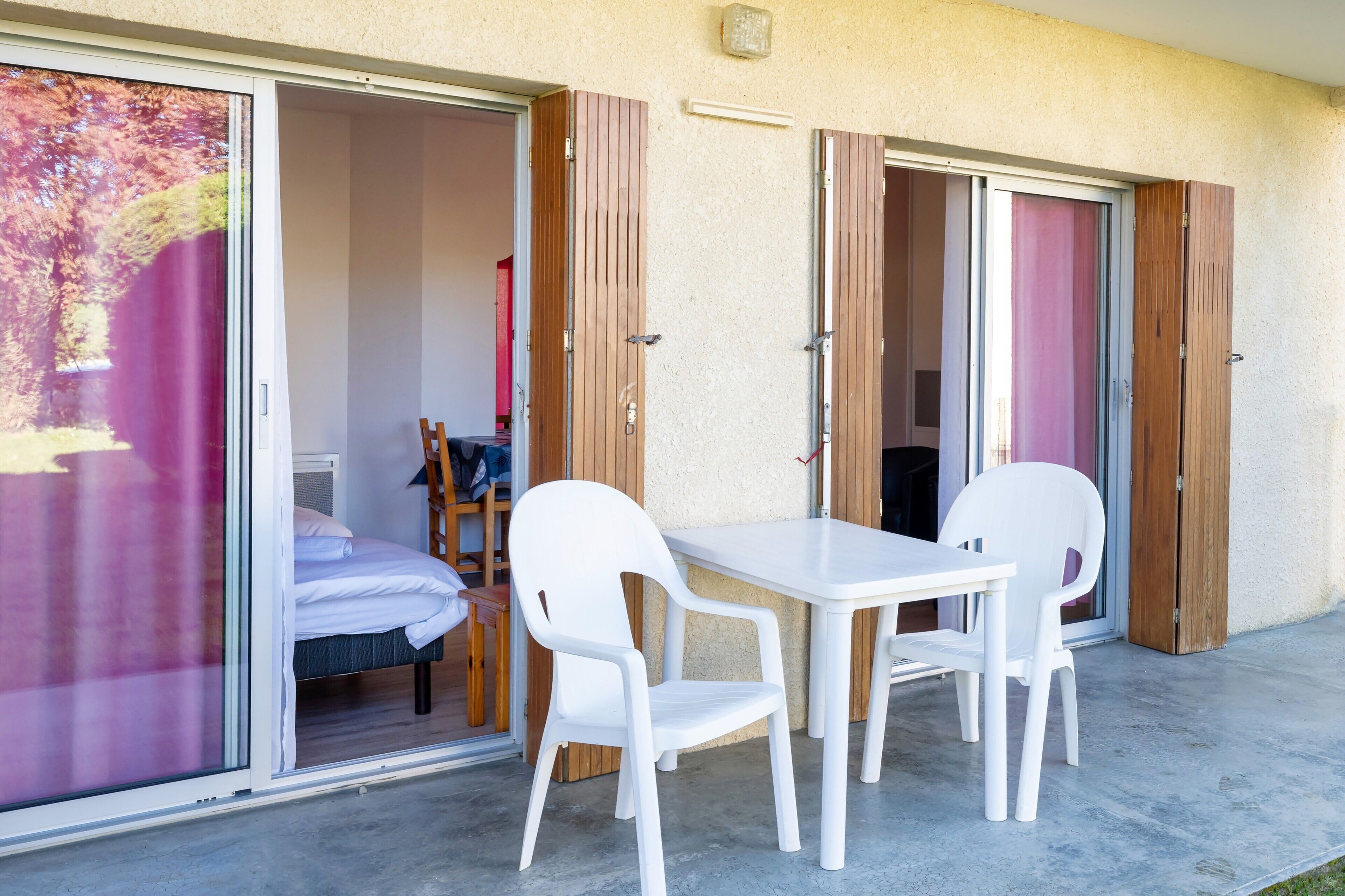 Une chambre avec un lit, une table et des chaises, et une porte-fenêtre coulissante donnant sur un balcon.