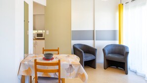 A compact living space with a dining table, two armchairs, a microwave, and a sliding door. - Cosy Studio with Balcony, Air Conditioning & Pool Table – Cazaubon (Cazaubon)