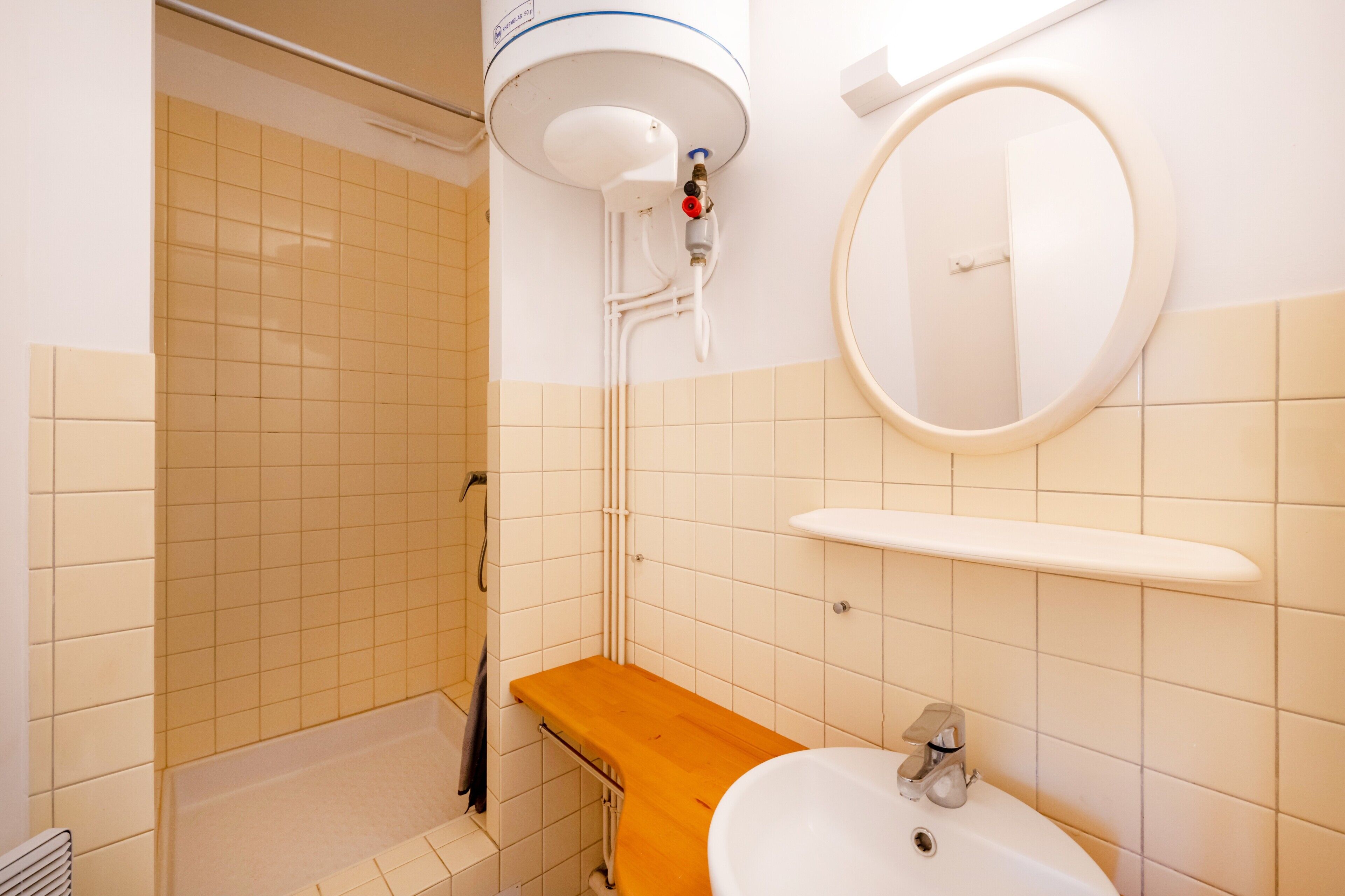 A bathroom with a shower, a sink, and a mirror.