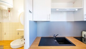 A modern kitchen with a sink, countertop, and white cabinets. - Cosy Studio with Balcony, Air Conditioning & Pool Table – Cazaubon (Cazaubon)