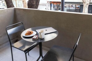 A balcony with a metal table, two chairs, a croissant, a cup, and a small box. - Soho VIllage en Palermo by Magno | 101 (Buenos Aires)