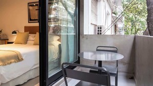 Un dormitorio con cama, mesita de noche y ventana.
