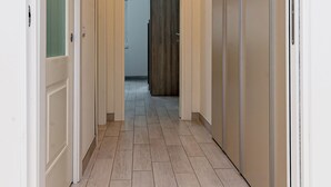 A hallway with a light-colored tiled floor, a door with frosted glass panels, and a wardrobe with a handle. - Luca Flat - Tiburtina Train Station (Rome)