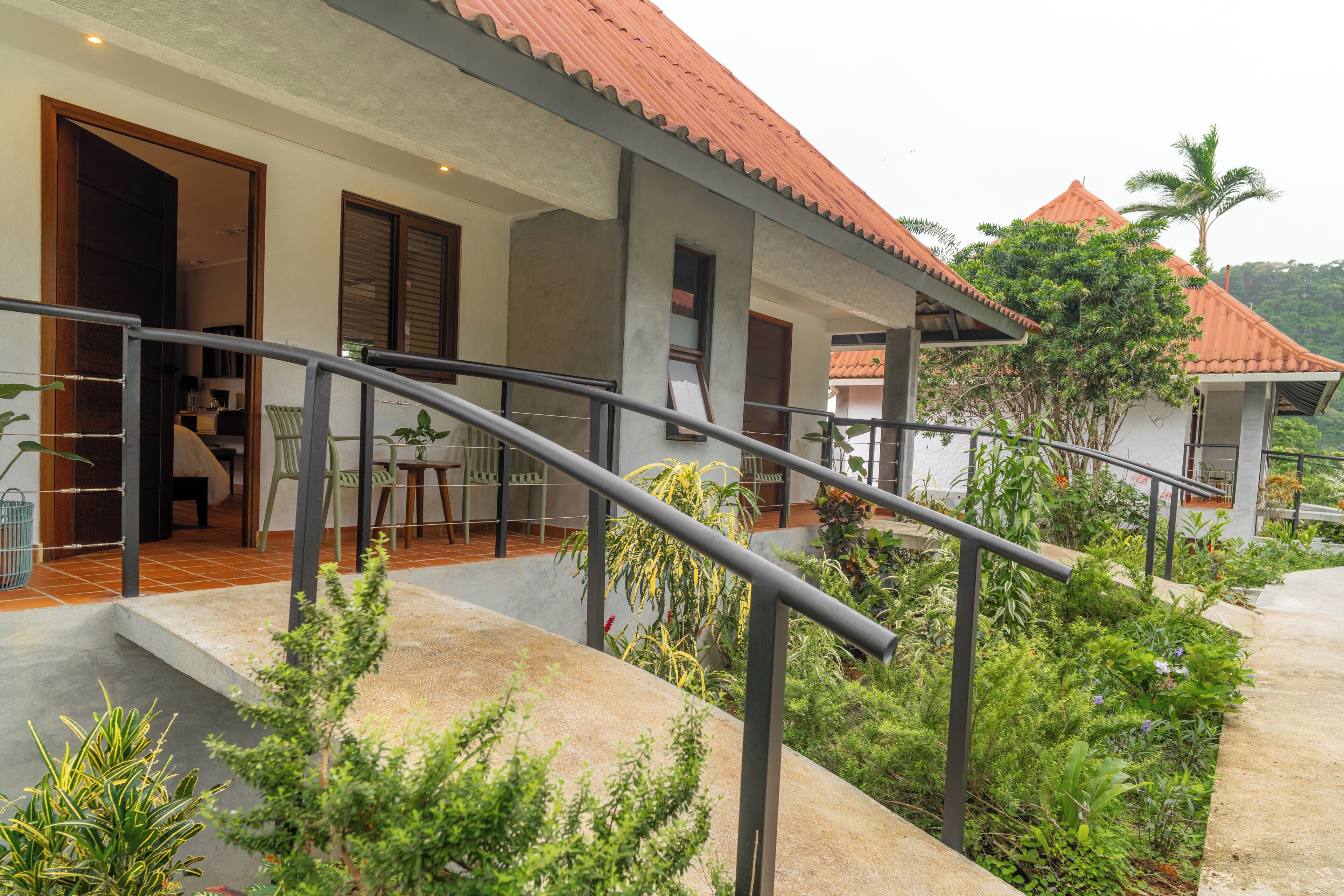 A modern house with a red-tiled roof, a covered porch, and a staircase leading to a second level.