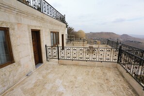 Une terrasse sur le toit agrémentée de balustrades décoratives, offrant une vue sur un dôme et un paysage montagneux en arrière-plan.