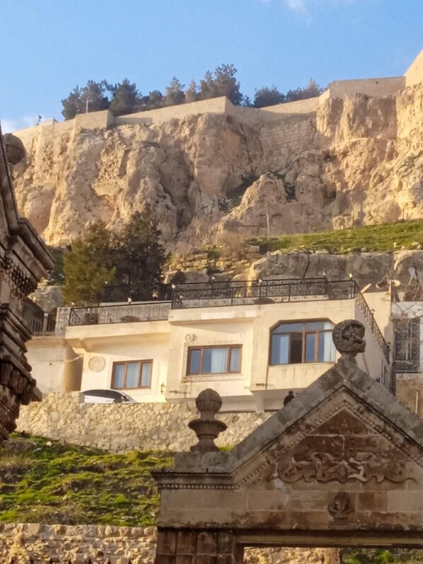 Un bâtiment en pierre doté d’un balcon et offrant une vue sur une colline rocheuse.