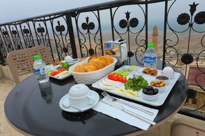 Ett bord dukat med frukostmat, en flaska vatten och en utsikt över en avlägsen byggnad.