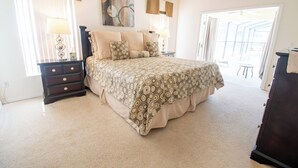Een slaapkamer met een groot bed, nachtkastje, een dressoir en een raam met gordijnen.