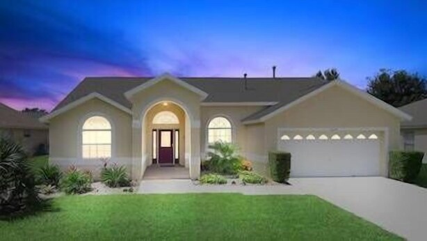 Een huis met twee verdiepingen, een voordeur, een garage en een verzorgd gazon.