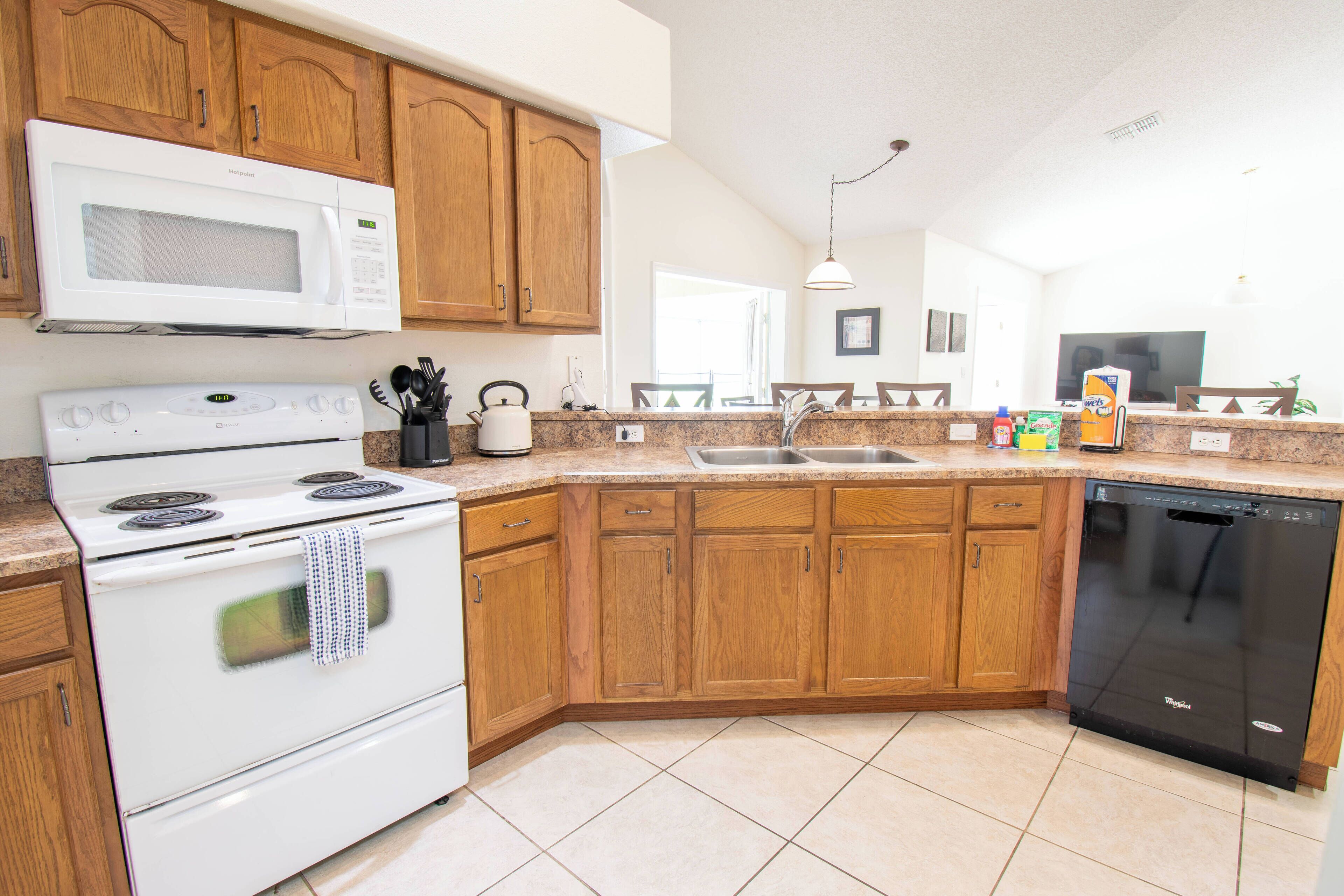 A kitchen with wooden cabinets, a microwave, stove, sink, and dishwasher.