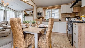 Una cocina moderna con comedor, armarios de madera, microondas y estufa.