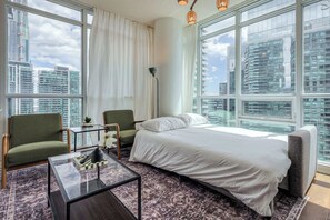 Relax in a cozy living room with a Smart TV and city views. - Downtown 2BR condo w/ city views & free parking (Toronto)