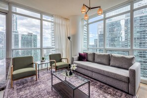 Relax in a cozy living room with a Smart TV and city views. - Downtown 2BR condo w/ city views & free parking (Toronto)