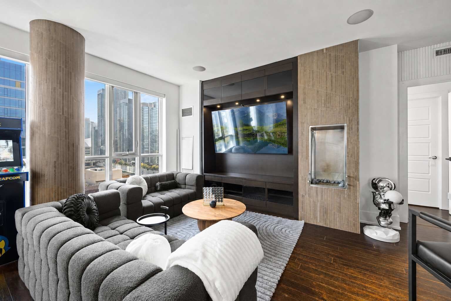 A modern living room with a sectional sofa, a flat-screen TV, and a fireplace.