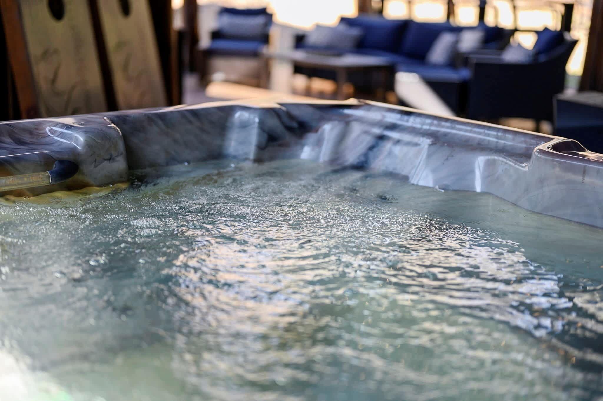 Una vasca idromassaggio con vista sull'acqua e una struttura in legno sullo sfondo.