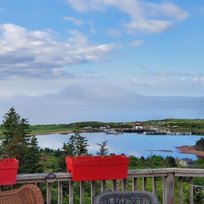 A lakeside view with a wooden deck, red planters, and boats docked at a marina. - Private, serene ocean view on 3 acres. Room for ten. Best local deal. (Inverness)