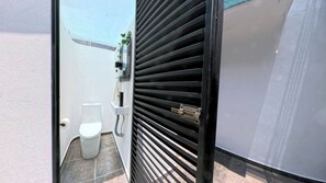 Une salle de bain avec des toilettes, un lavabo et une fenêtre avec des stores.