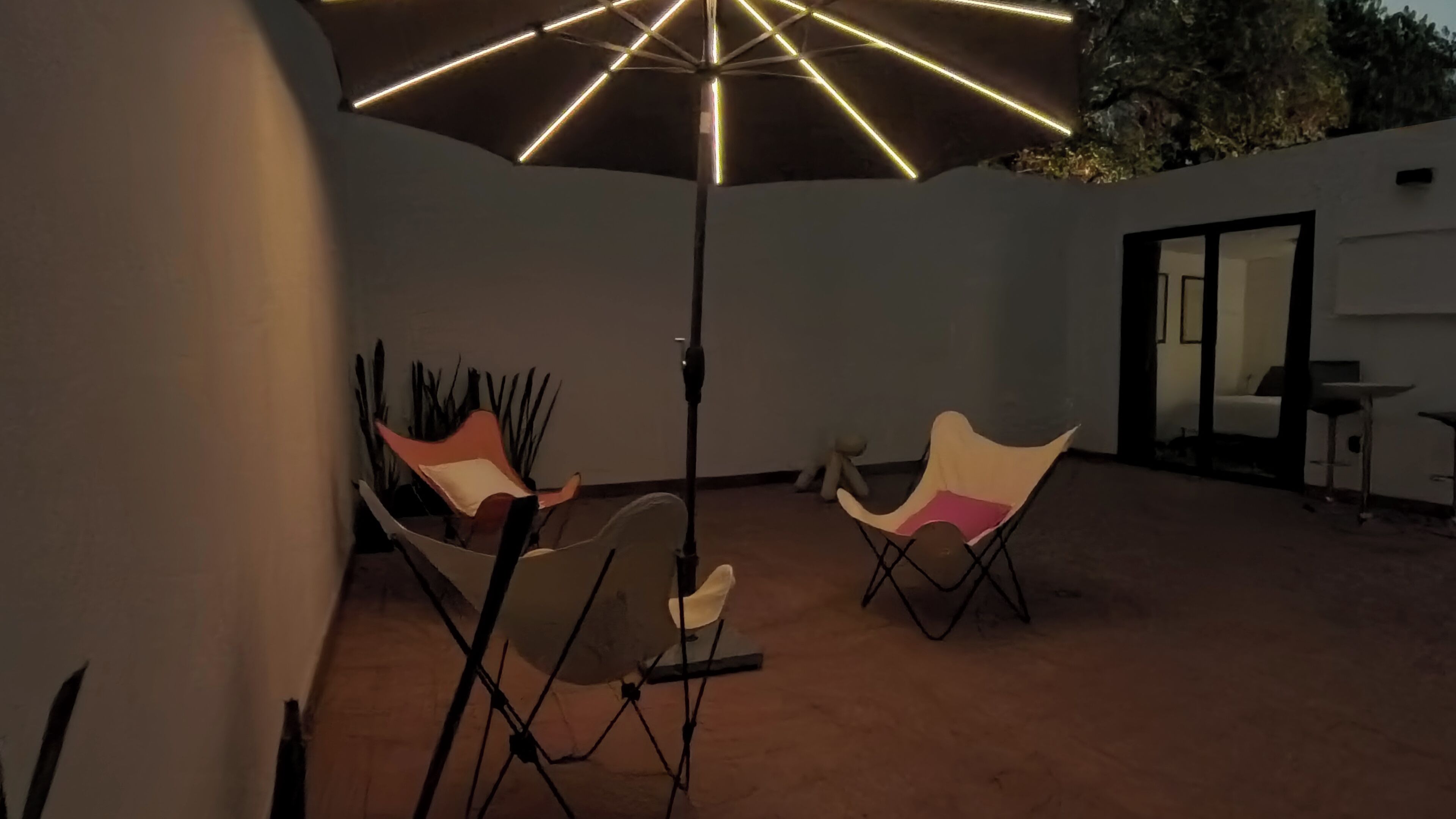 Een terras met twee stoelen, een tafel, een grote parasol en een stenen muur.