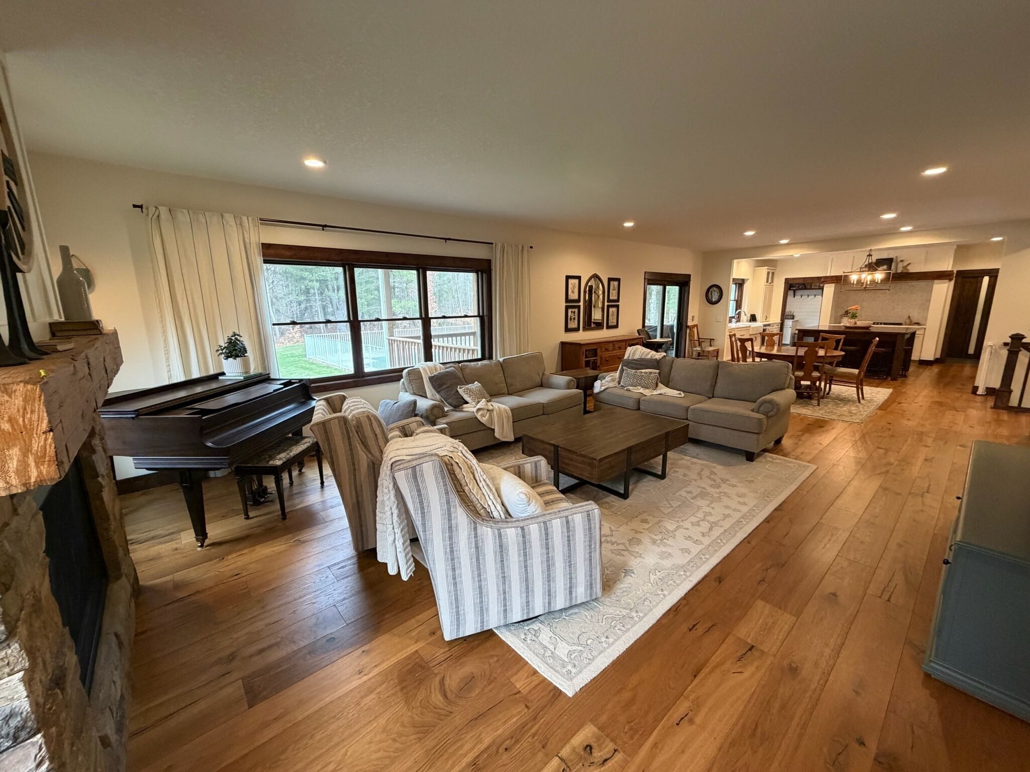 A spacious living room with a grand piano, sofas, a coffee table, and a fireplace.