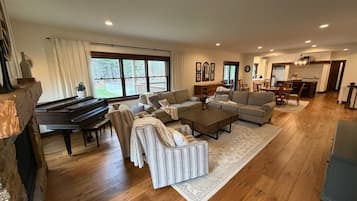 A spacious living room with a grand piano, sofas, a coffee table, and a fireplace.