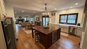 A spacious kitchen with a central island, wooden flooring, and a large window.