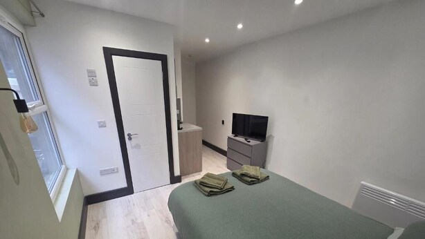 Ein Schlafzimmer mit einem Bett, einem Fernseher, einem Schminktisch und einer Tür.