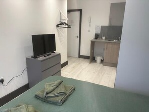 A room with a bed, a TV on a stand, a small desk, and a bathroom visible in the background. - Room-1066 Apart Hotel - Double Room With (Hastings)
