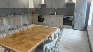 Una cocina moderna con armarios grises, una mesa de comedor de madera y un horno empotrado.