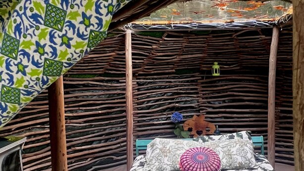 Ein Zimmer mit einem Bett, einer hölzernen Bank und einem Strohdach.