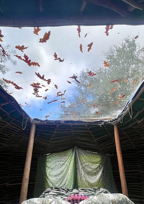 Una habitación con tragaluz, una cama con ropa de cama estampada y una cortina verde.
