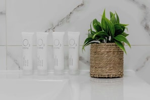 Vier Showergels von Ozone und ein Blumentopf auf einer Marmorplatte.