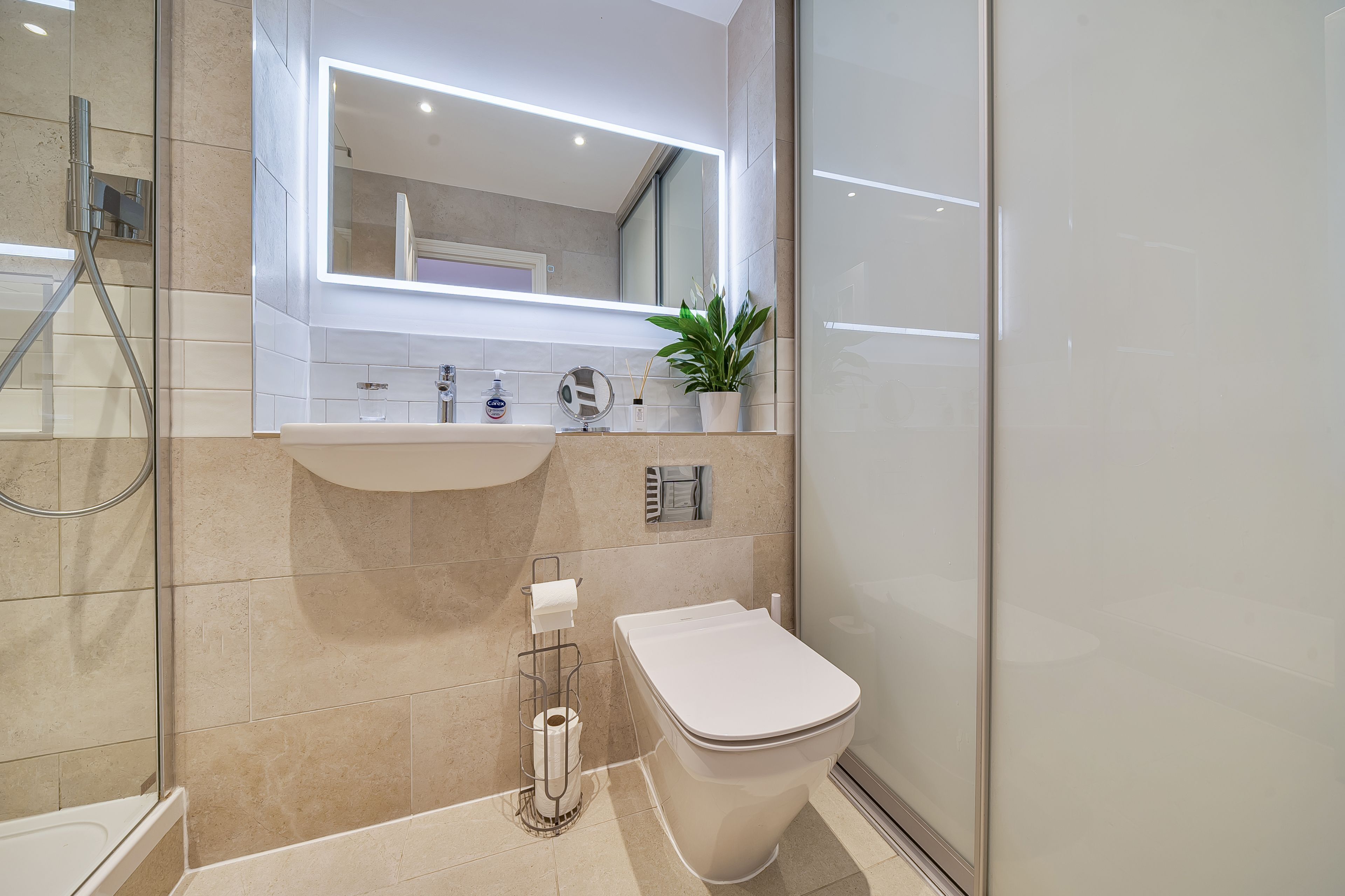 A modern bathroom with a glass shower enclosure, a white sink, and a toilet.
