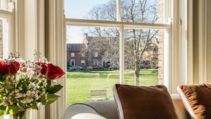 A room with a large window, a sofa, and a vase of flowers. - 3 Monteagle - sleeps 6 guests  in 3 bedrooms (Wells-next-the-Sea)