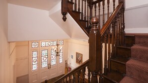 A wooden staircase with a chandelier, patterned carpet, and a door with stained glass windows. - 3 Monteagle - sleeps 6 guests  in 3 bedrooms (Wells-next-the-Sea)