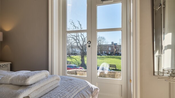 A bedroom with a bed, a window, and a view of a park. - 3 Monteagle - sleeps 6 guests  in 3 bedrooms (Wells-next-the-Sea)