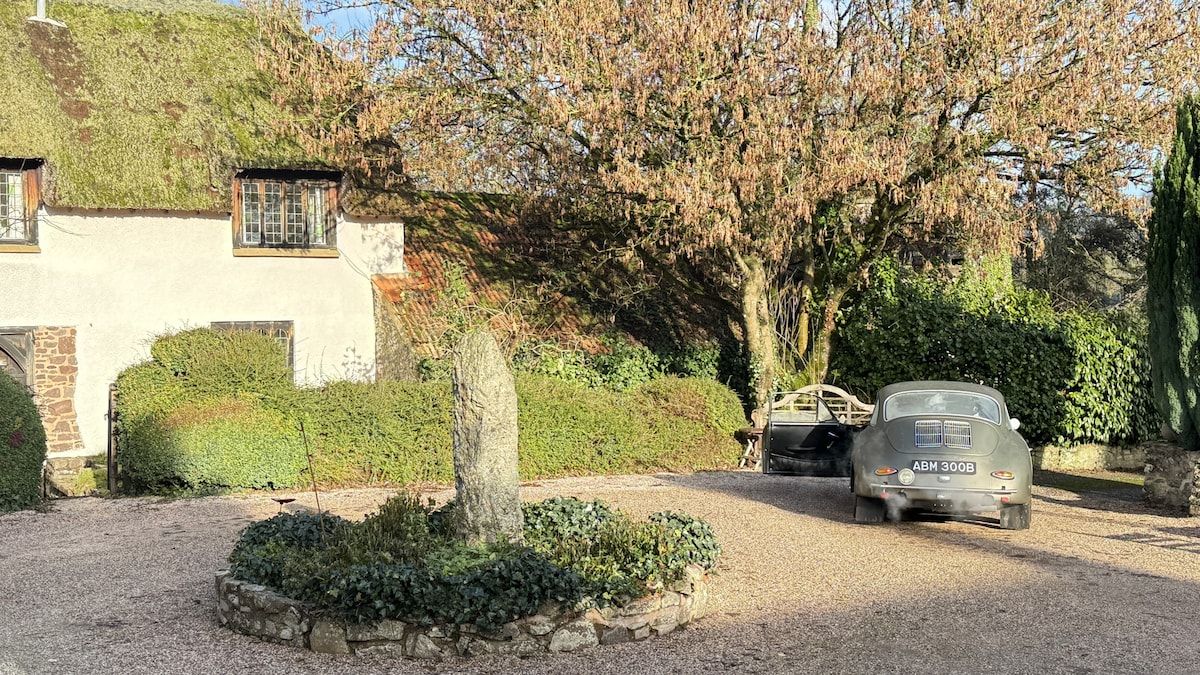 Une maison avec une façade en pierre, une allée gravillonnée et une voiture garée.