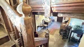 A high-ceilinged room with wooden beams, a fireplace, and a dining area with a table and chairs.