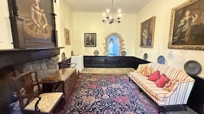 A room with a fireplace, a sofa, a patterned rug, and framed artwork on the walls.