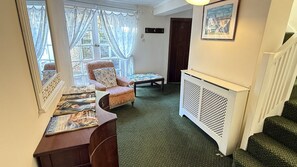 A room with a chair, a small table, a radiator, a staircase, and a door.