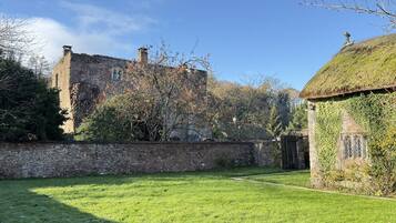 A stone building with ivy-covered walls and a thatched-roof structure.