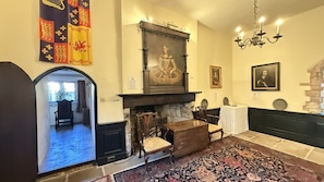 A room with a fireplace, a framed portrait, and a chandelier.