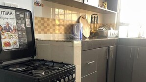 Una cucina con piano cottura nero, zoccolo di piastrelle e una finestra.