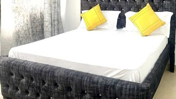 Un letto con una testiera trapuntata, due cuscini e una coperta bianca.