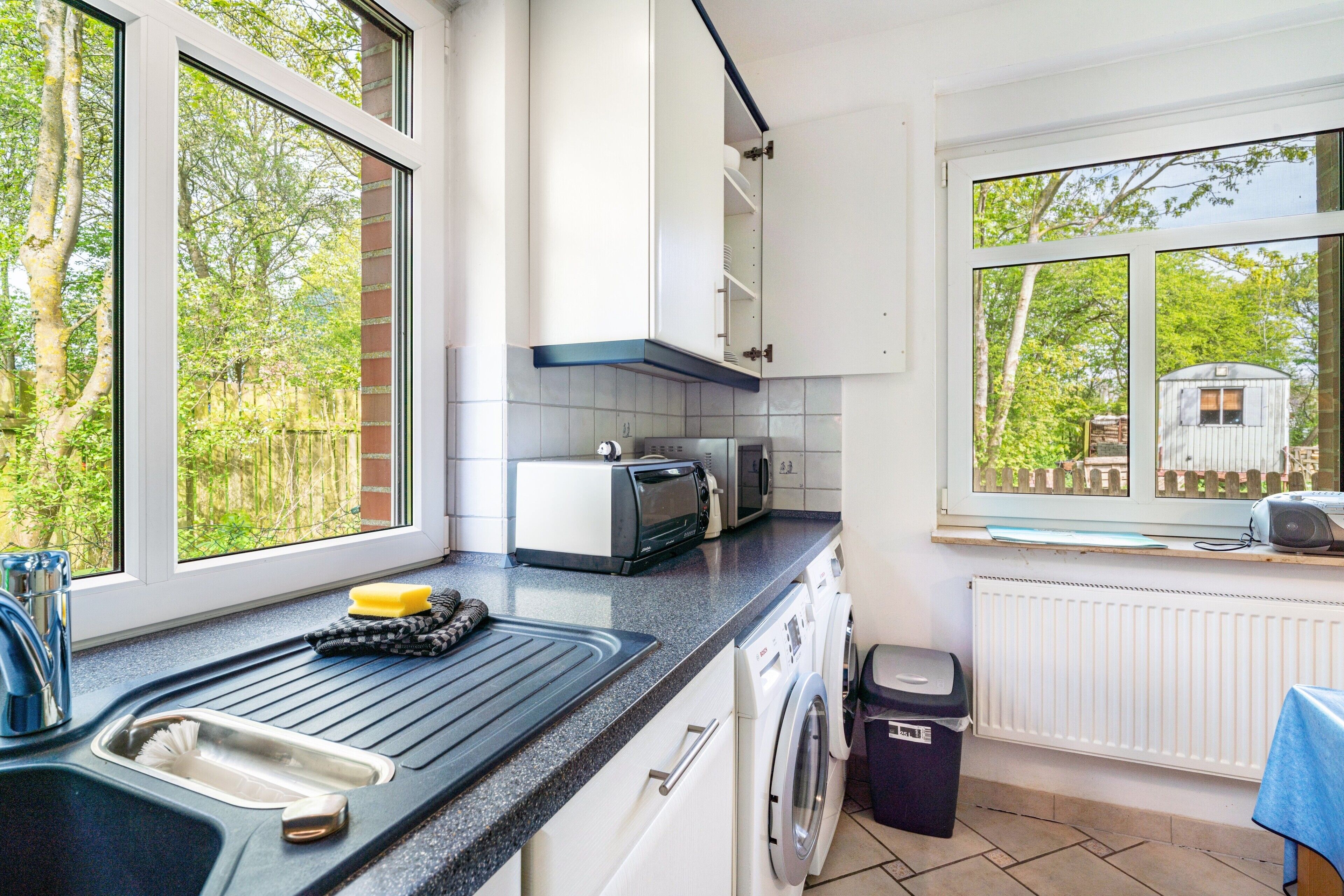 A compact kitchen with a sink, toaster, and washing machine.
