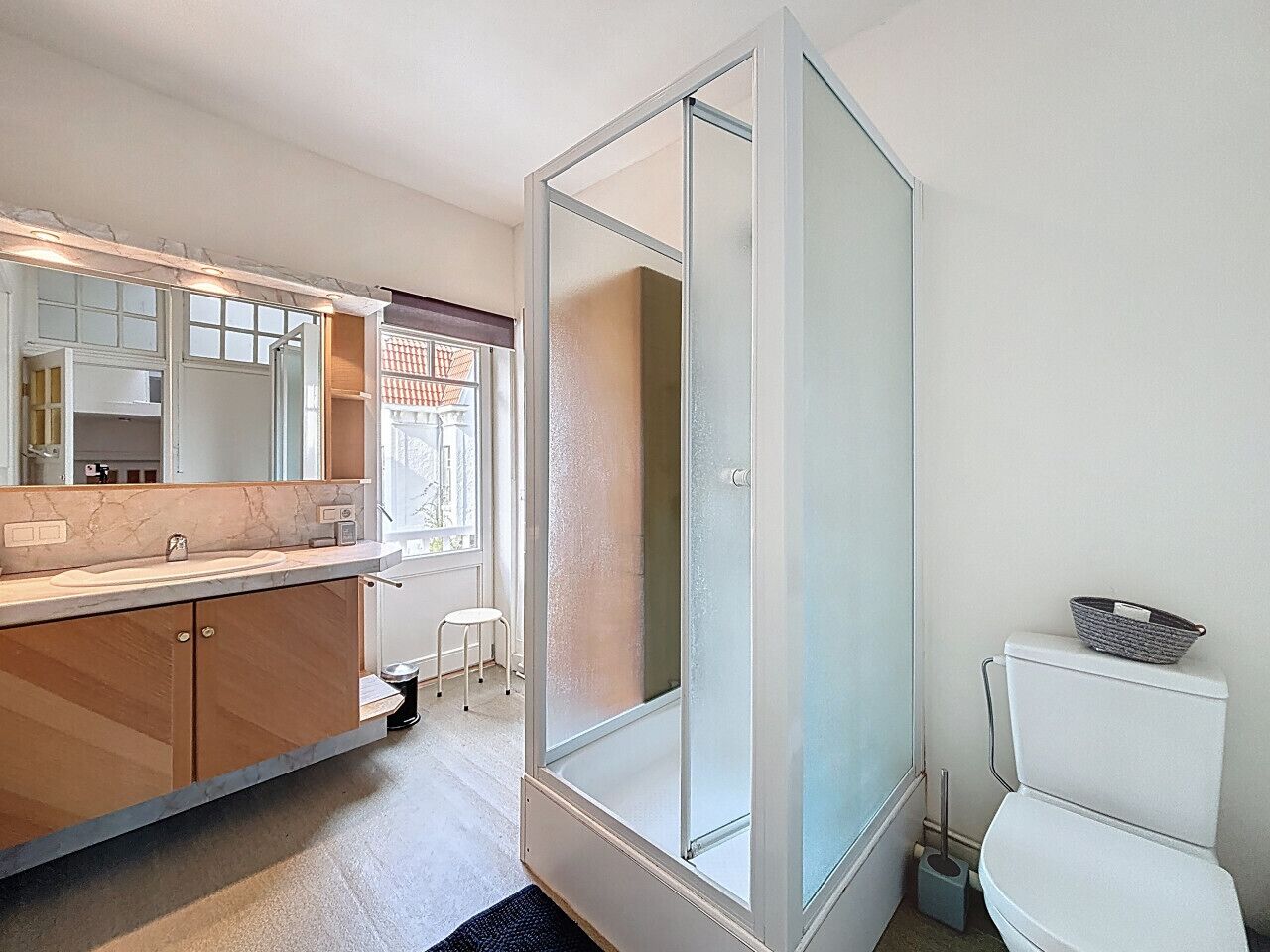 Un baño moderno con cabina de ducha de vidrio, inodoro y lavabo con espejo.