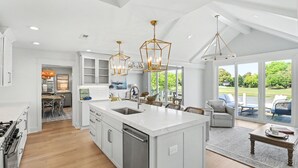 Una cocina moderna con una isla grande, luces colgantes y vistas al exterior.