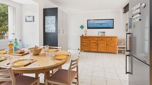A modern kitchen with a dining area, a TV mounted on the wall, and a refrigerator. - 900m beach, house 4 adults / 2 kids (Sarzeau)