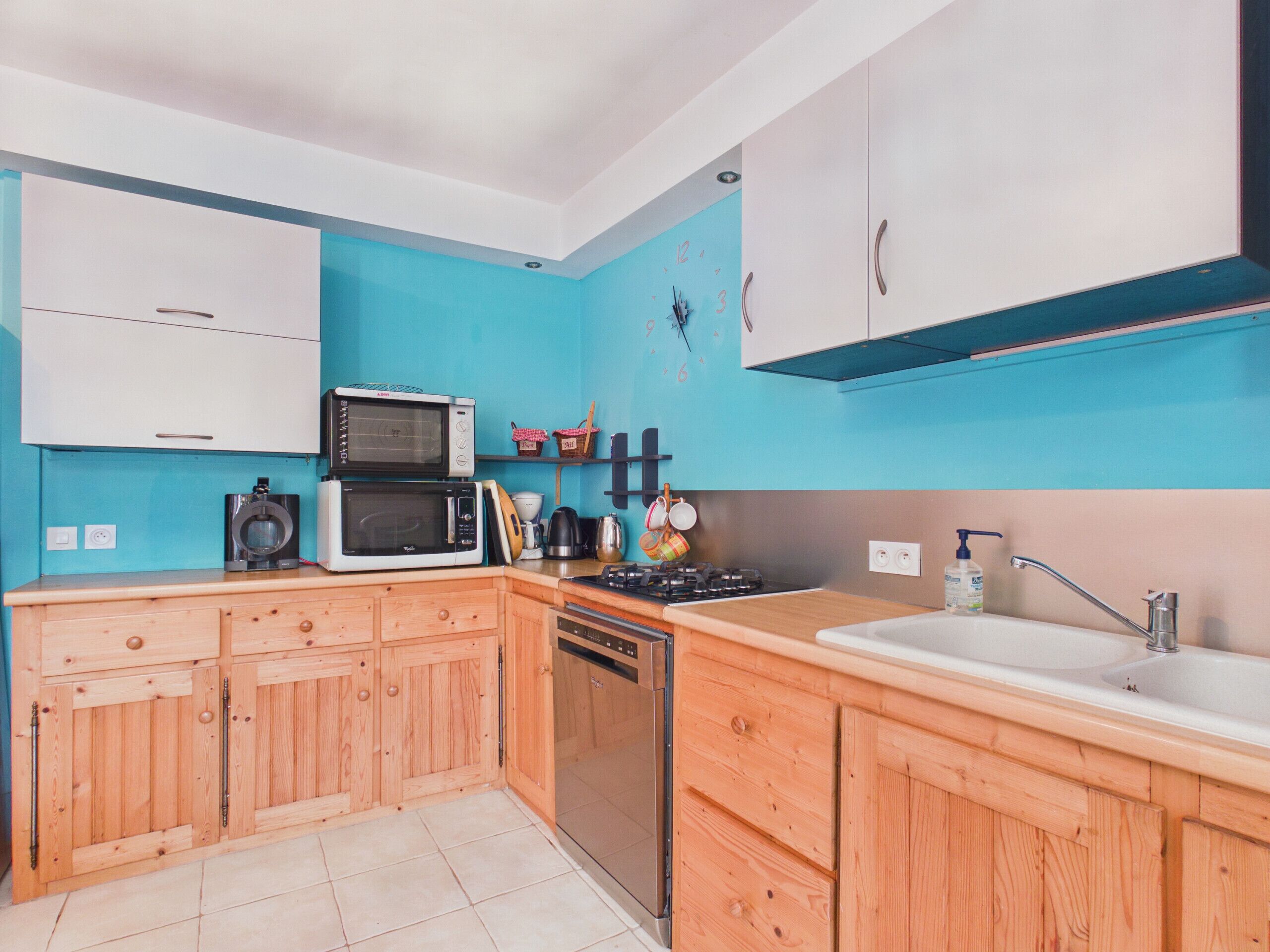 Une cuisine avec des meubles de rangement en bois, un four à micro-ondes, une cuisinière et un évier.