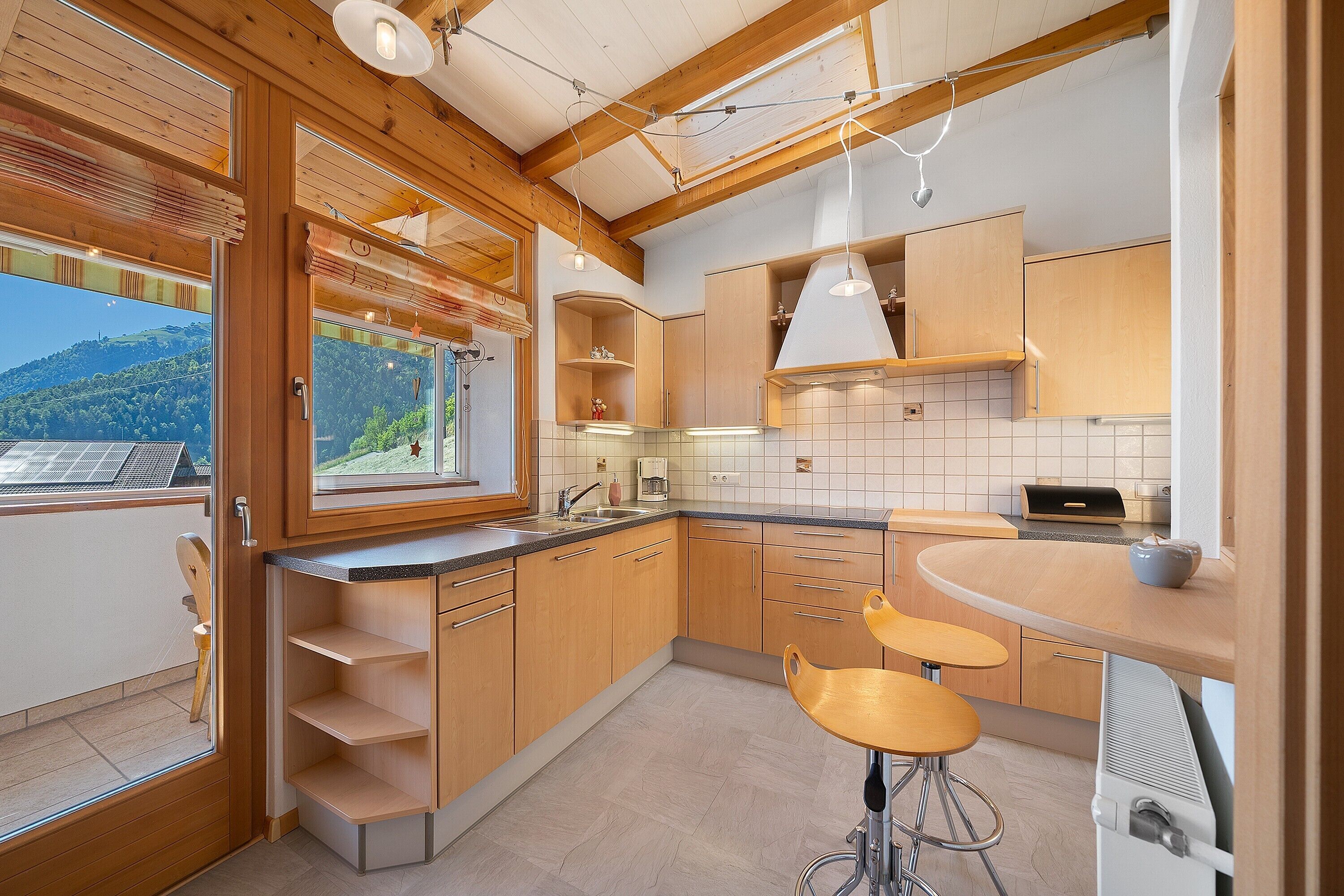 Cozinha moderna com armários de madeira, uma janela grande e um espaço de refeições com banquetas.